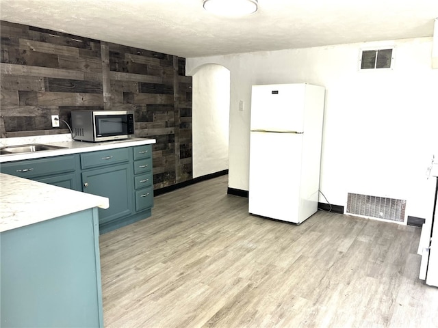 7351/2 7th Ave, Coraopolis, PA 15108 - kitchen with freestanding refrigerator, light countertops, light wood finished floors, stainless steel microwave, and arched walkways