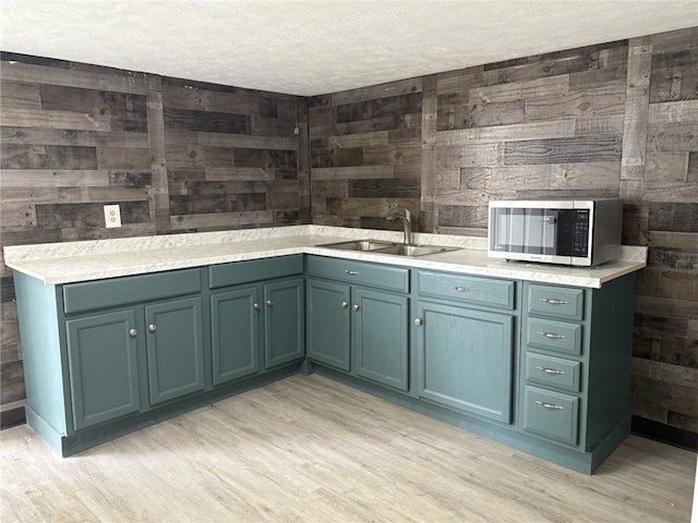 7351/2 7th Ave, Coraopolis, PA 15108 - kitchen featuring wooden walls, light wood-type flooring, a textured ceiling, stainless steel microwave, and light countertops
