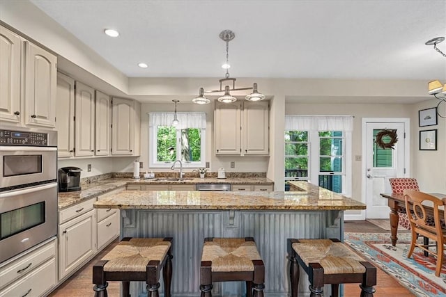 2001 Buckingham Dr, Marshall, PA 16046 - kitchen featuring a breakfast bar area, double oven, pendant lighting, light stone counters, and a center island