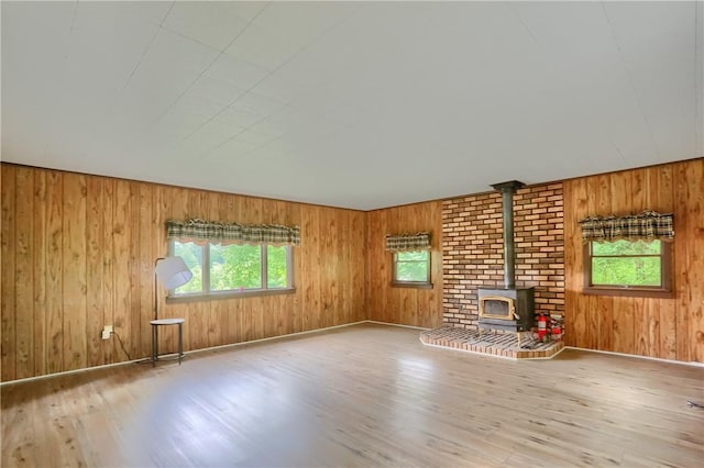 1405 Three Degree Rd, Adams Twp, PA 16059 - unfurnished living room featuring a wood stove, healthy amount of natural light, wood finished floors, and wooden walls