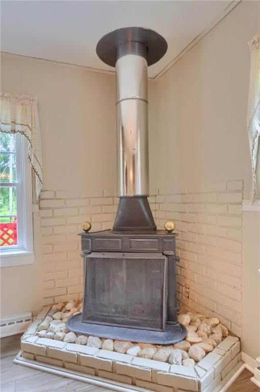 1405 Three Degree Rd, Adams Twp, PA 16059 - detailed view of a wood stove, baseboard heating, ornamental molding, and wood finished floors