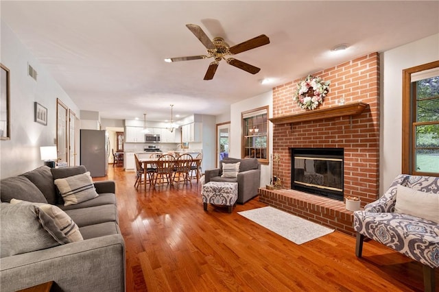 103 Cool Springs Ln, Penn Twp, PA 15636 - living area featuring light wood finished floors, a brick fireplace, and a ceiling fan