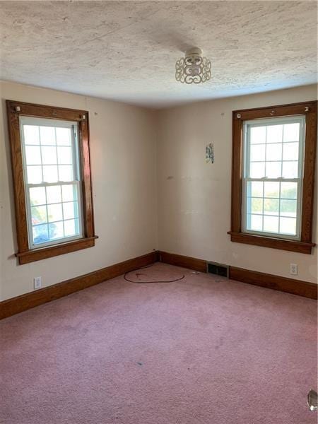 carpeted empty room featuring a textured ceiling