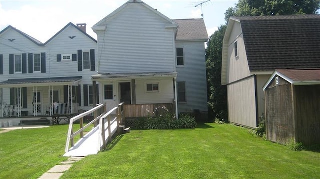 rear view of property featuring a lawn and covered porch