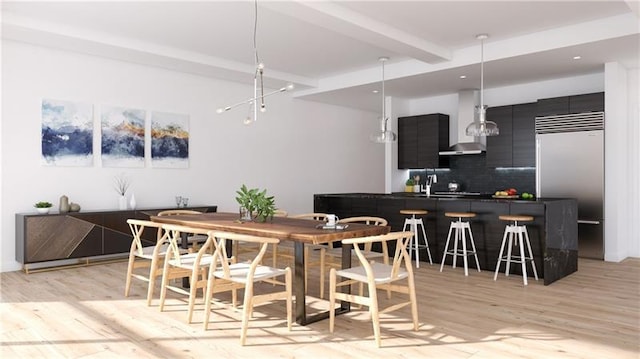 interior space featuring built in refrigerator, pendant lighting, light hardwood / wood-style floors, wall chimney exhaust hood, and tasteful backsplash