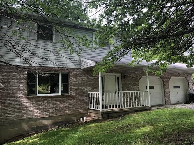 view of front of house with covered porch, a front yard, and a garage