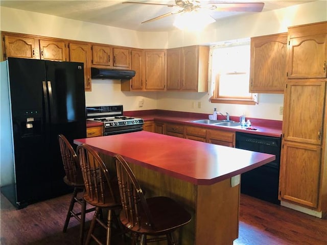 kitchen featuring ceiling fan, exhaust hood, dark wood-type flooring, black appliances, and a center island