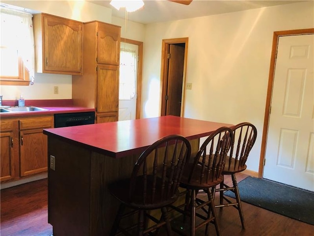 kitchen featuring ceiling fan, dark wood-type flooring, a kitchen bar, sink, and dishwasher