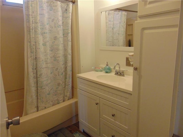 bathroom featuring vanity with extensive cabinet space, shower / bathtub combination with curtain, and hardwood / wood-style flooring