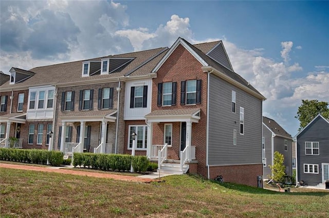 townhome / multi-family property with covered porch and a front lawn