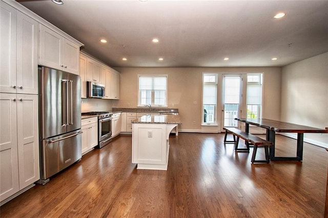 kitchen with stainless steel appliances, a healthy amount of sunlight, white cabinets, and dark hardwood / wood-style flooring