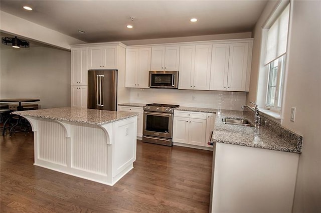 kitchen featuring light stone countertops, appliances with stainless steel finishes, white cabinets, dark hardwood / wood-style floors, and sink