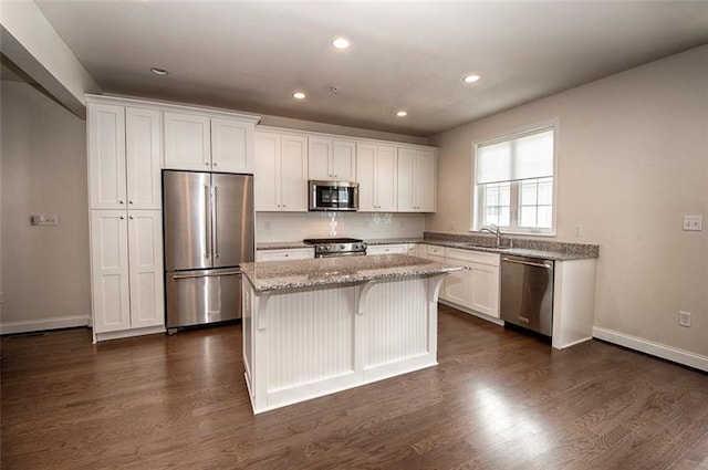 kitchen featuring appliances with stainless steel finishes, a center island, white cabinetry, and dark hardwood / wood-style flooring