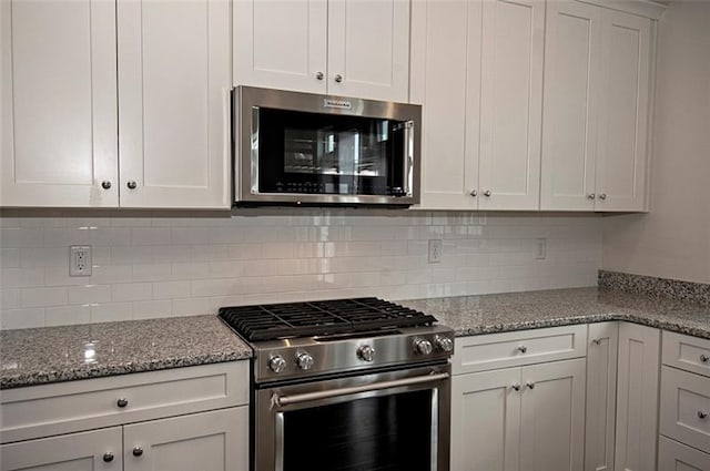 kitchen featuring white cabinets, backsplash, light stone countertops, and appliances with stainless steel finishes