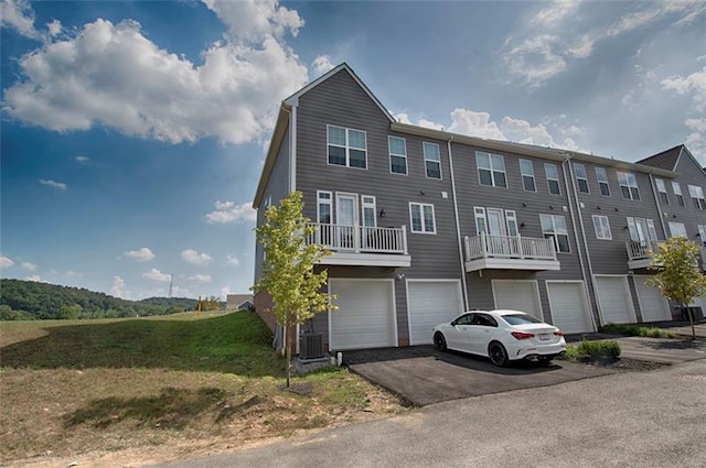 view of front of house featuring a balcony, central air condition unit, and a garage