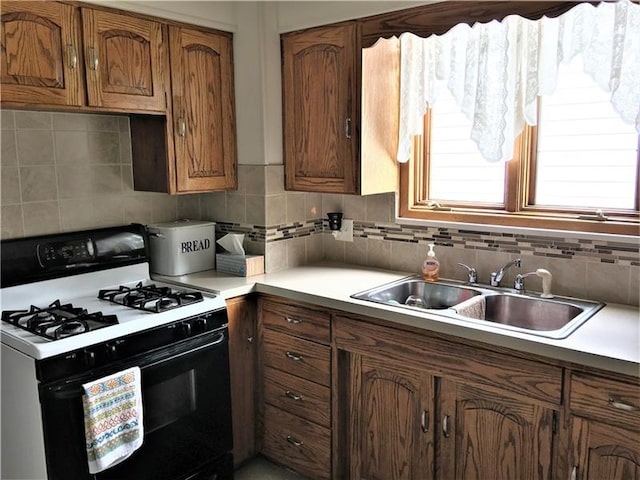 kitchen with sink, tasteful backsplash, and white gas stove