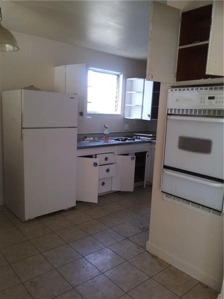 kitchen with white appliances, white cabinetry, and light tile floors