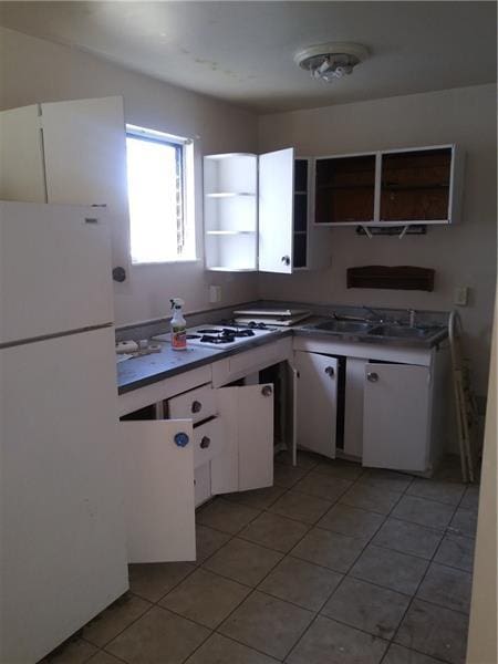 kitchen featuring light tile flooring, white appliances, and white cabinets