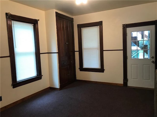 unfurnished room featuring dark carpet