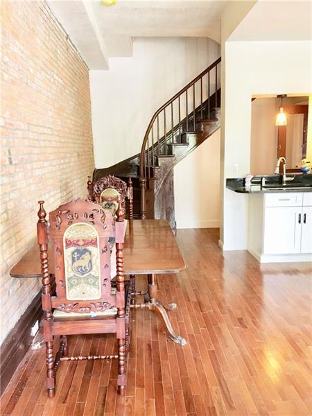 dining area featuring brick wall, light wood-type flooring, and sink