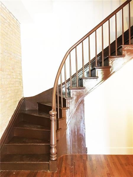 staircase with brick wall and dark hardwood / wood-style floors