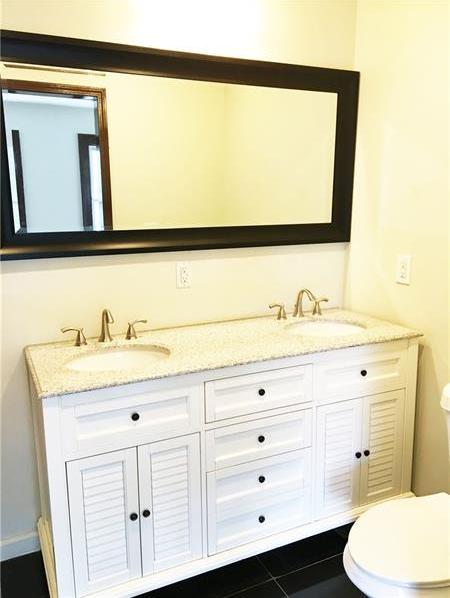 bathroom with toilet, dual vanity, and tile flooring