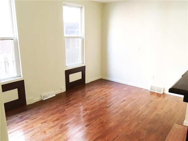 empty room with dark wood-type flooring and a healthy amount of sunlight