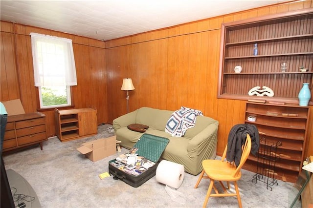 living area with light carpet and wooden walls