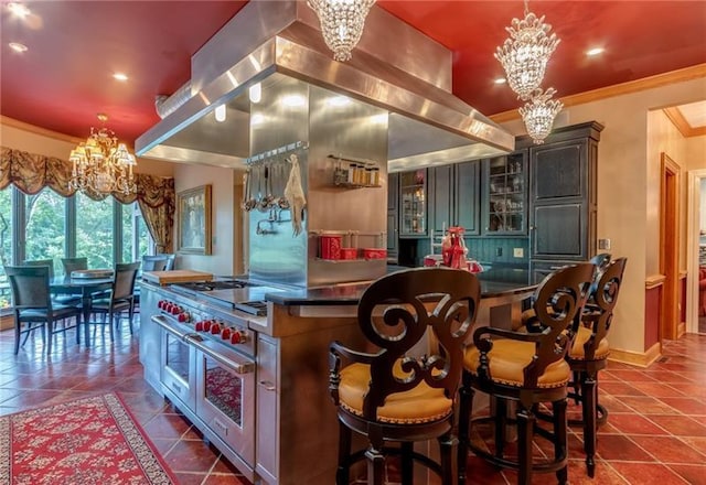 kitchen with dark tile flooring, an inviting chandelier, ornamental molding, and island exhaust hood