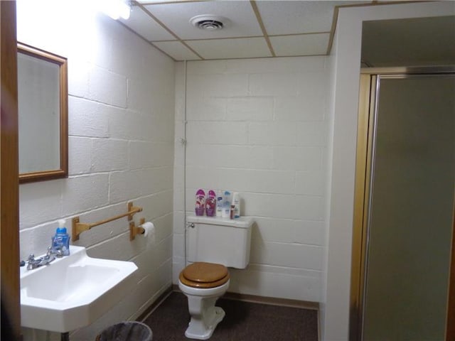 bathroom featuring toilet, a shower with shower door, a drop ceiling, and sink