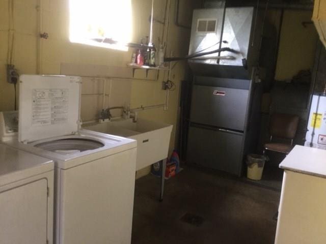 washroom with independent washer and dryer, water heater, and sink