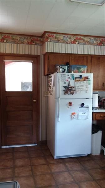 kitchen featuring white refrigerator and dark tile flooring