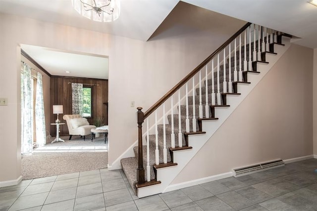 stairway with wooden walls, light colored carpet, and a notable chandelier