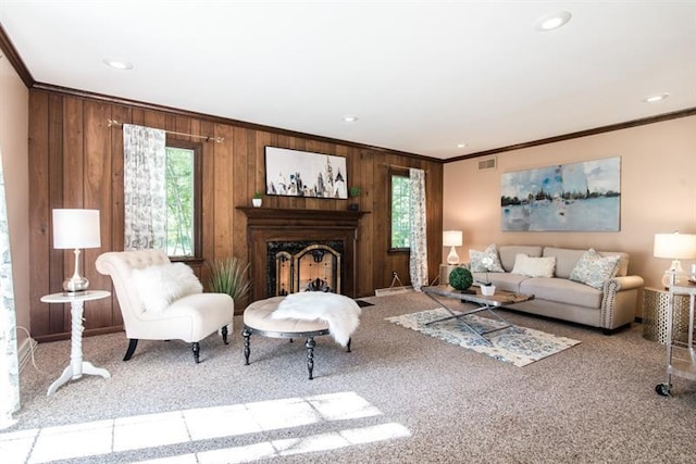 carpeted living room with wooden walls, ornamental molding, and a wealth of natural light