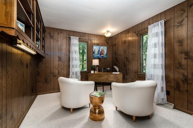 sitting room with light carpet and wood walls