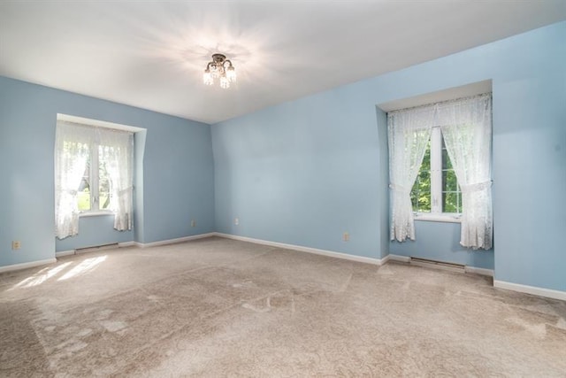 carpeted spare room with a notable chandelier and plenty of natural light