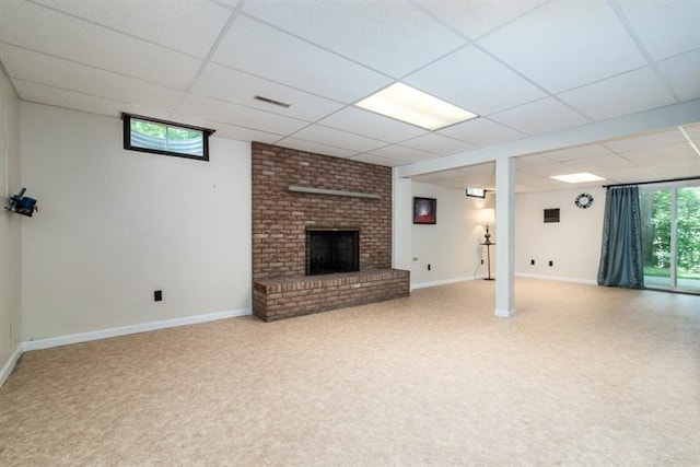 unfurnished living room with a drop ceiling, brick wall, a fireplace, and light colored carpet