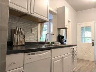 kitchen with dishwasher, white cabinetry, light hardwood / wood-style flooring, and plenty of natural light