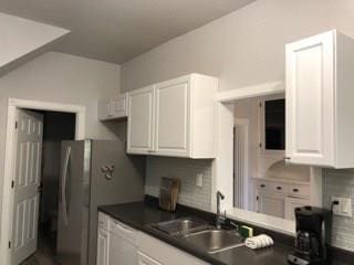 kitchen with sink, stainless steel refrigerator, and white cabinets