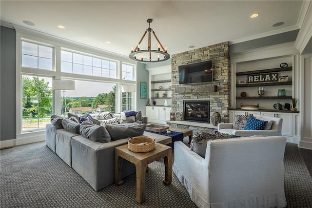 carpeted living room featuring built in features, a stone fireplace, crown molding, and an inviting chandelier