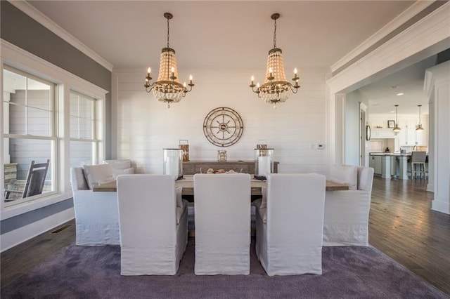 dining room with plenty of natural light, dark wood-type flooring, ornamental molding, and a notable chandelier