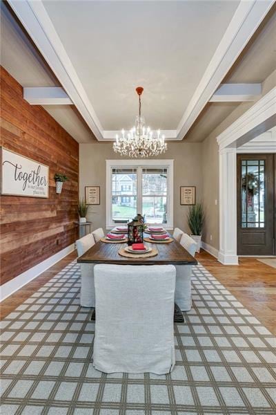 dining space with a notable chandelier, wood walls, and light hardwood / wood-style floors