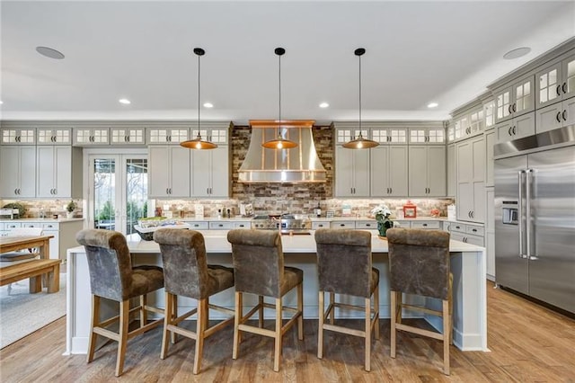 kitchen featuring pendant lighting, a kitchen island, built in fridge, and wall chimney exhaust hood