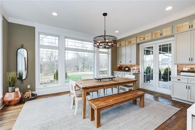 dining room featuring dark hardwood / wood-style flooring, french doors, an inviting chandelier, and crown molding