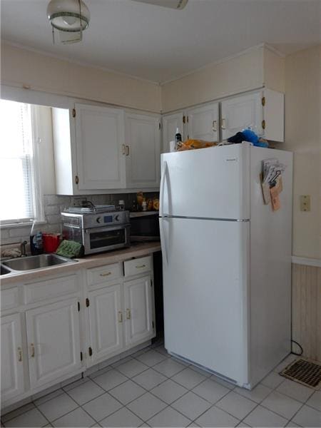 kitchen featuring white cabinetry, light tile flooring, sink, and white refrigerator