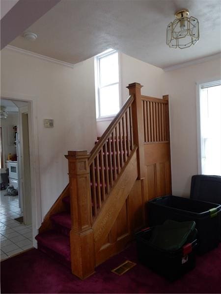 staircase featuring dark tile flooring and a chandelier