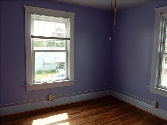 unfurnished room with dark wood-type flooring and a healthy amount of sunlight