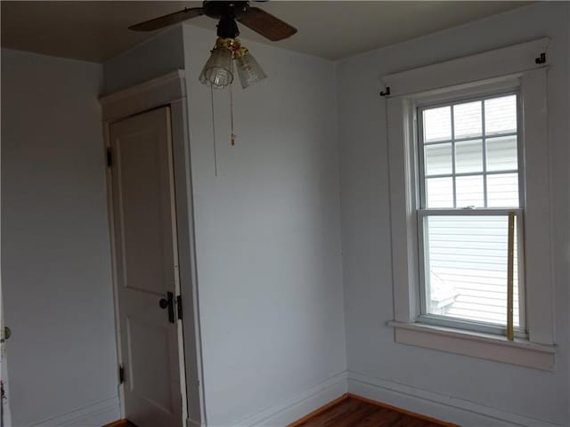 empty room with dark hardwood / wood-style flooring, ceiling fan, and plenty of natural light