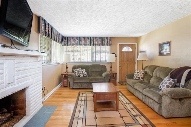 living room featuring light hardwood / wood-style floors, a textured ceiling, and a fireplace