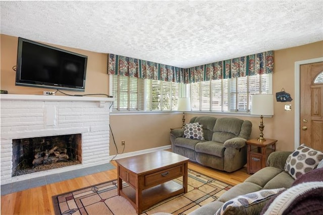 living room with a healthy amount of sunlight, light hardwood / wood-style flooring, a textured ceiling, and a fireplace